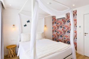 a bedroom with a white bed with a canopy at Palheiro 81 in Costa Nova