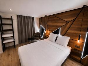 a bedroom with a white bed and a wooden headboard at APARTÉ HOTEL Dijon Sud in Chenôve