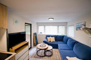 a living room with a blue couch and a tv at MOLO RESORT KEMPING in Osiek