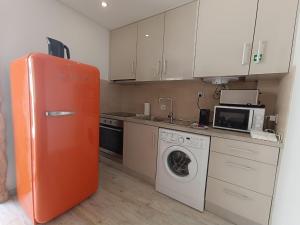 a kitchen with an orange refrigerator and a washing machine at Tomarhousing - Secret Garden in Tomar +2 photos