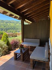 a patio with a wooden pergola with two beds and a table at Apartamentos Fuente La Pipa in Avín