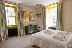 a bedroom with a white bed and two windows at The Lodge at Dabton House in Carronbridge