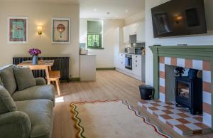 a living room with a fireplace and a kitchen at The Lodge at Dabton House in Carronbridge