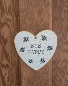 a heart shaped sign with bees on a wooden wall at BEE HAPPY available with shared bathroom in Glastonbury