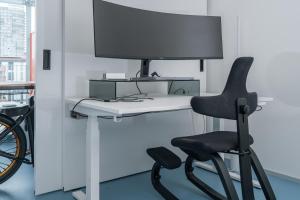 a black chair sitting next to a desk with a monitor at Modern Zurich Apt with Balcony View & Workspace in Zurich