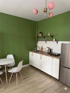 a kitchen with green walls and a table and chairs at The Bay Apartments in Cholpon-Ata