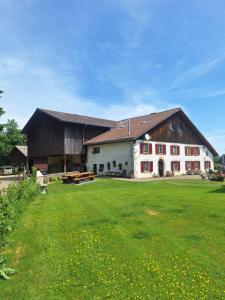 a large barn with a large grass field in front of it at Chambres d'hôtes Les Fontaines in Tramelan