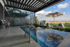 a house with a swimming pool with an umbrella at Y HOUSE SUITES in Mishmār Hāyardin