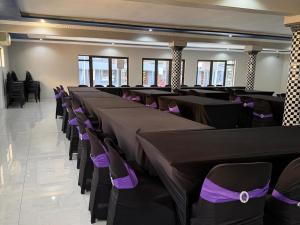 a banquet hall with black tables and purple chairs at Giyani Shamba Lodge in Giyani +14 photos