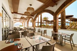 a restaurant with tables and chairs and a view of the ocean at AluaSun Doblemar in La Manga del Mar Menor