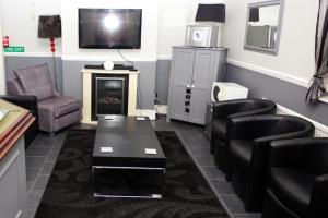 a waiting room with chairs and a table and a tv at Mallowview guest house in Cleethorpes