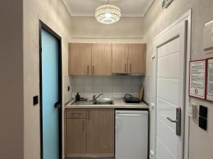 a small kitchen with wooden cabinets and a sink at ANNA ROOMS (Villa Anna) in Nea Vrasna
