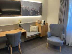 a room with two chairs and a desk with a tv at Gästehaus Klingler in Besigheim