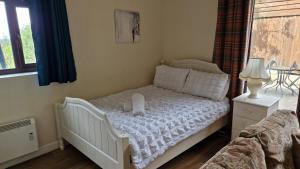 a bedroom with a bed with a white crib at The Nook - Farm Park Stay with Hot Tub & Dome in Swansea