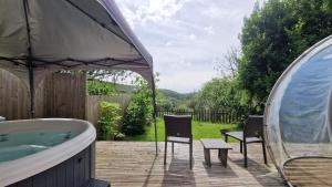 a tub and chairs on a patio with a table and chairs at The Nook - Farm Park Stay with Hot Tub & Dome in Swansea