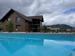 a house with a swimming pool in front of a house at SOKIL HOUSE будинок з чаном та літнім басейном in Slavske