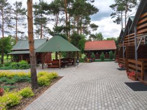 a brick walkway with a pavilion and a building with a green roof at Domki Piaskowa in Boszkowo-Letnisko +35 photos