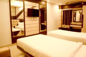 a hotel room with two beds and a mirror at Hotel S G International in Dhanbād