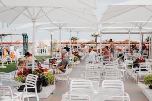 a marquee with white tables and chairs and people sitting at Hotel Marina in Lido di Jesolo