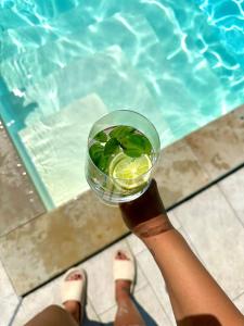 a person holding a glass with a drink next to a swimming pool at Hedona227 in Perlez