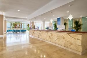 a hotel lobby with a reception counter and tables at AluaSun Doblemar in La Manga del Mar Menor +60 photos