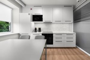 a white kitchen with white cabinets and a table at K4 Jonava Rooms in Jonava