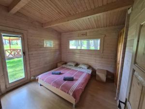 a bedroom with a bed in a wooden cabin at Giruliu kopa in Melnragė