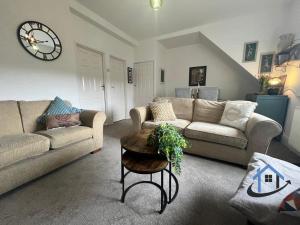 a living room with two couches and a clock on the wall at 28 Victoria Terrace, Bedlington, ground floor in Bedlington +28 photos