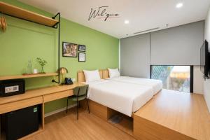 a bedroom with a bed and a desk with a television at Wilque Hotel Hanoi in Hanoi
