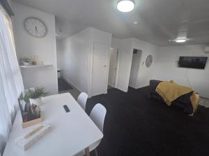 a room with a table and a bed and a clock at Te Whare Whitiora in Hamilton