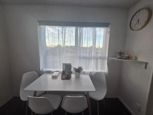 a white table and chairs in a room with a window at Te Whare Whitiora in Hamilton