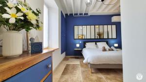 a blue bedroom with a bed and a vase of flowers at Le Tarare in Guipy
