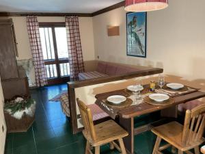 ein Wohnzimmer mit einem Tisch und einem Sofa in der Unterkunft Sestriere-Sises Lodges, Appartamenti Moderni, vicino alle piste in Sestriere