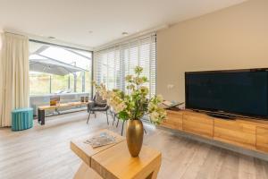 a living room with a television and a vase with flowers at Gerritslanderdijkje 39a in Westermient