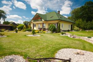 a house with a green roof on a yard at Dworek Biebrzański in Augustów