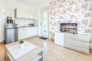 a kitchen with white cabinets and red flowers on the wall at Ferienwohnung Sonneneck in Kachlin