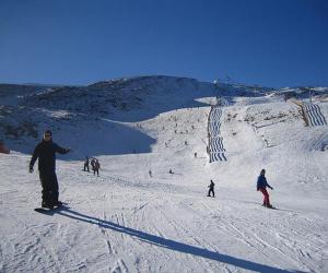 a group of people skiing down a snow covered slope at La Cuadrina de Anton in Pajares