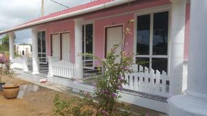 ein rosa und weißes Haus mit einer Veranda in der Unterkunft Iz Budget 2 in Kampung Kuala Besut