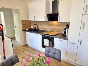 a kitchen with white cabinets and a table with pink flowers at Nicos Ferienwohnung in Grevesmühlen - ABC628 in Grevesmühlen +13 photos