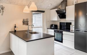 a kitchen with white cabinets and black appliances at Nice Home In Haderslev With Sauna in Haderslev