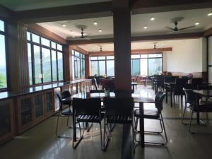 a dining room with tables and chairs and windows at HOTEL GREENERY VIEW in Gangtok
