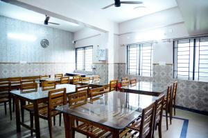 a dining room with tables and chairs and windows at Aldur Residency in Aldūr