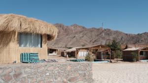 a hut with chairs and mountains in the background at Viva La Vida Beach Camp in Nuweiba