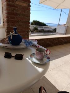 a table with a tea pot and a cup and glasses at Surf House in Artemida