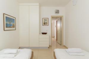 two beds in a room with white walls at Mamad Comfort & Terrace In Ramat Aviv By Feelhome in Tel Aviv