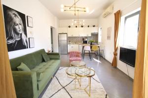 a living room with a green couch and a kitchen at Design & Balcony In City Center By Feelhome in Tel Aviv