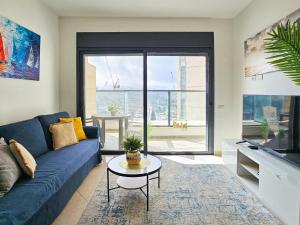 a living room with a blue couch and a table at Mamad Family Friendly New Condo By Feelhome in Yerushalayim