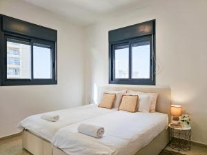 a white bedroom with two windows and a bed at Mamad Family Friendly New Condo By Feelhome in Yerushalayim