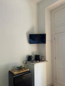 a room with a refrigerator and a tv on the wall at The Velvet Suite Alkmaar in Alkmaar