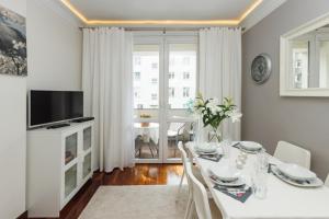 a white dining room with a table and a television at Apartament Abrahama in Gdynia
